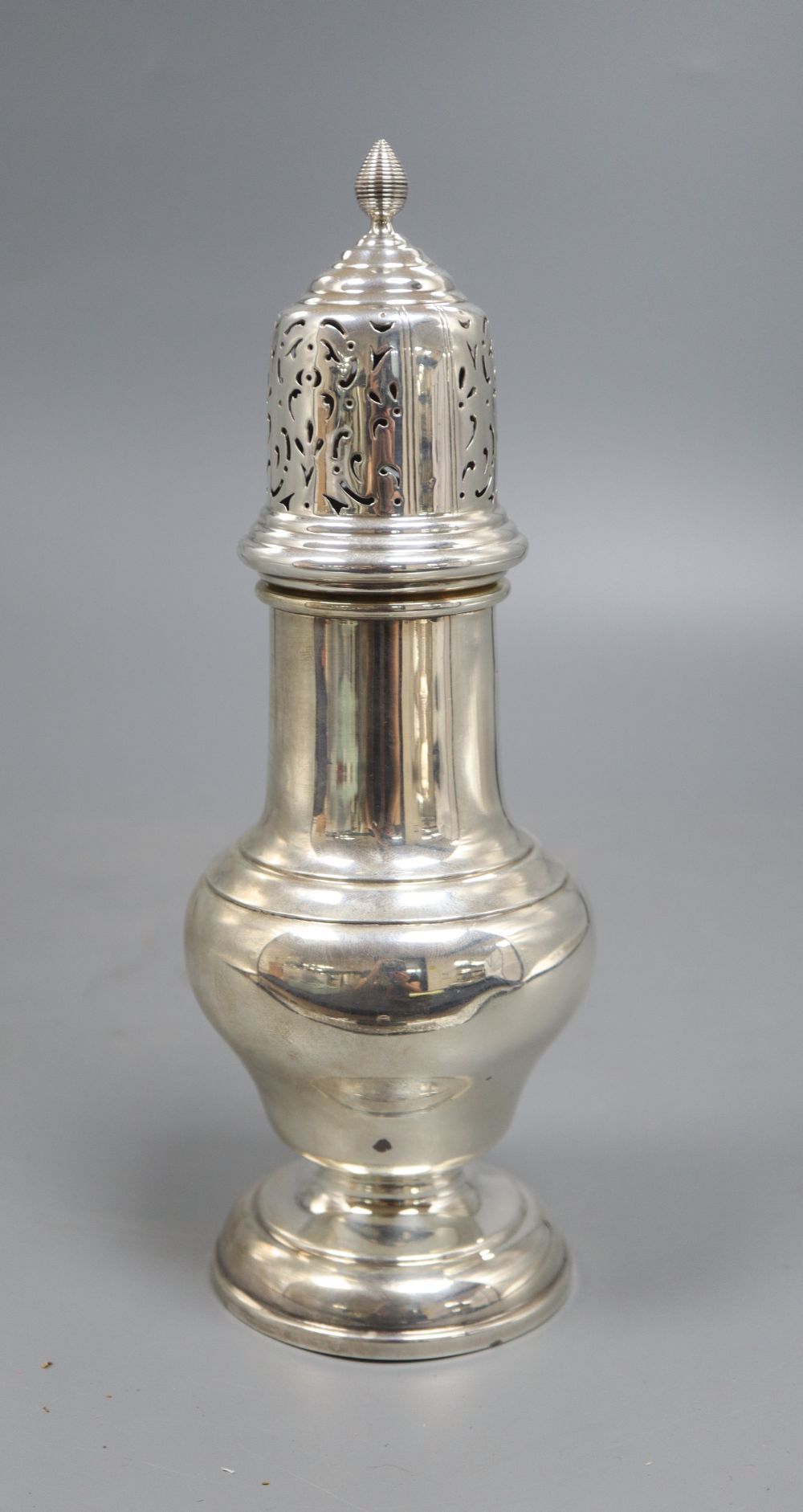 A silver vase shape sugar shaker, with pierced domed cover, ribbed finial on circular base, Birmingham 1932, 7.6oz., height 23cm